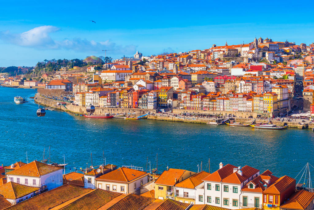 Vista da Ribeira do Porto, com casas coloridas e barco no rio Douro.